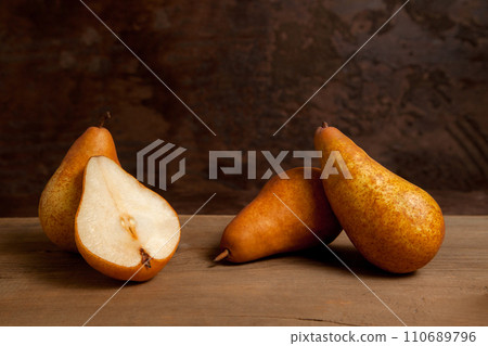 Whole and halves of pears on wooden background.. 110689796
