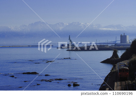 Himi Line Kiha 40 series diesel train running leisurely under the Tateyama mountain range that towers like a wall_Photographed on 12/30/2023 110690196