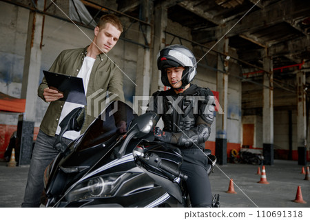Male instructor teaching young biker at personal lesson at motorcycle school Male instructor teaching young biker at personal lesson at motorcycle school 110691318