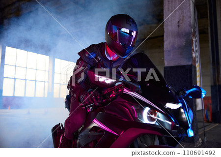 Portrait of motor biker driving sport motorcycle in neon light 110691492