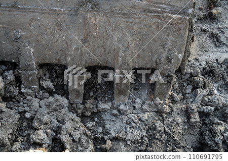 Closeup dirty bucket of backhoe working at construction site. Bucket teeth of backhoe digging soil. Crawler excavator digging on soil. Excavating machine. Earthmoving machine. Excavation vehicle. Closeup dirty bucket of backhoe working at construction site. Bucket teeth of backhoe digging soil. Crawler excavator digging on soil. Excavating machine. Earthmoving machine. Excavation vehicle. 110691795