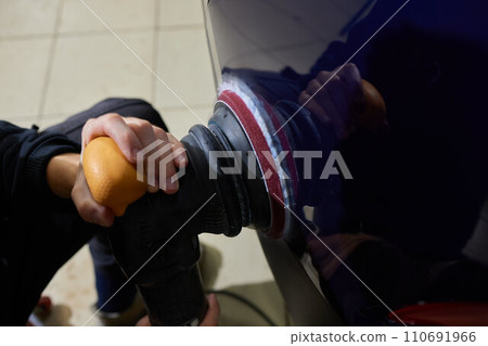 Man with an orbital polisher in car workshop polishing car closeup Man with an orbital polisher in car workshop polishing car closeup 110691966