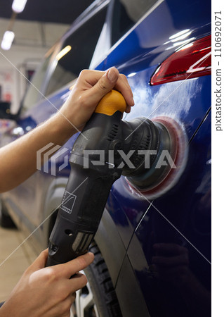 Man with an orbital polisher in car workshop polishing car closeup Man with an orbital polisher in car workshop polishing car closeup 110692071