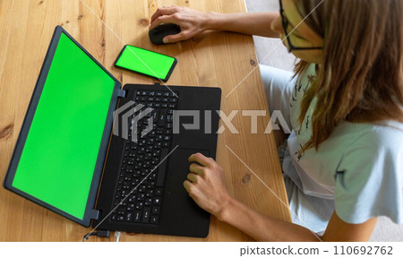 Top view young girl working or studying using her laptop and smartphone with mock up green screens. 110692762