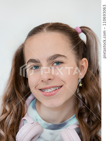 Portrait of smiling beautiful teenage girl with braces listening music in headphones, audiobook, lecture. 110693063