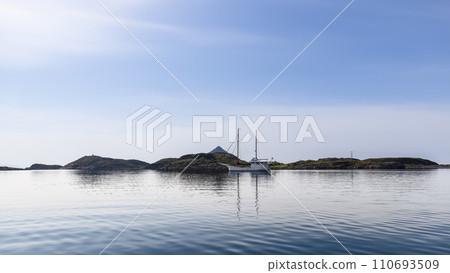 A serene sailboat rests in Norway's Lofoten waters under a clear sky 110693509