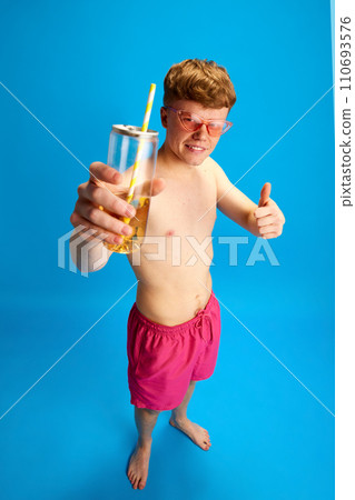 Portrait of young redhead man in stylish pink sunglasses standing with lemonade against blue studio background. Enjoyment Portrait of young redhead man in stylish pink sunglasses standing with lemonade against blue studio background. Enjoyment 110693576