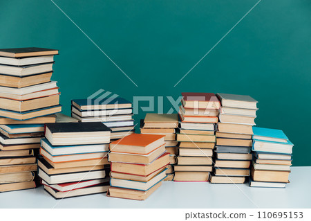 Stacks of old educational books in library on green background Stacks of old educational books in library on green background 110695153