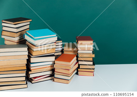 Stacks of old educational books in library on green background Stacks of old educational books in library on green background 110695154