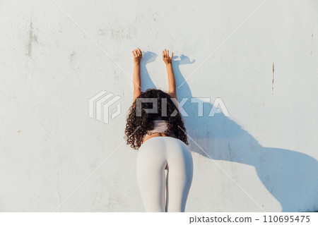 Woman doing yoga gymnastics against the wall with her back Woman doing yoga gymnastics against the wall with her back 110695475