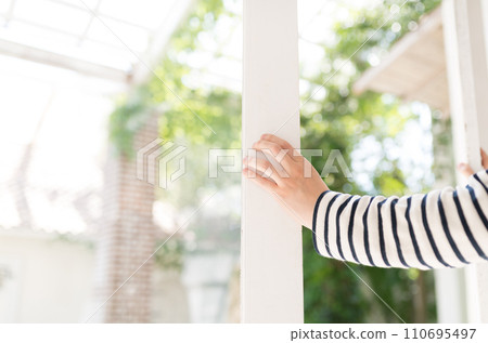 Portrait of a person opening a white frame window from a bright interior 110695497