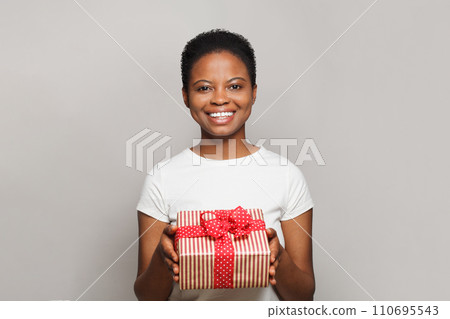 Cheerful happy young woman with gift present box standing on white background Cheerful happy young woman with gift present box standing on white background 110695543
