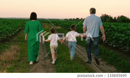 Mother father and sons stroll through plantation in evening after sunset 110695695
