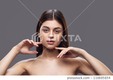Young attractive, tender lady with neutral make up posing looking at camera against grey studio background. Concept of natural beauty people Young attractive, tender lady with neutral make up posing looking at camera against grey studio background. Concept of natural beauty people 110695854