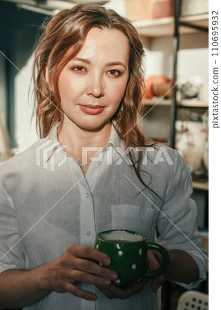 Relaxed woman with a mug of tea in the sunlight. Beautiful brunette woman with closed eyes, coffee break. 110695932