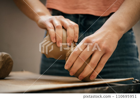 The ceramist s hands tear and divide soft, raw white clay into pieces. Preparing for clay modeling in the workshop, close-up The ceramist s hands tear and divide soft, raw white clay into pieces. Preparing for clay modeling in the workshop, close-up 110695951