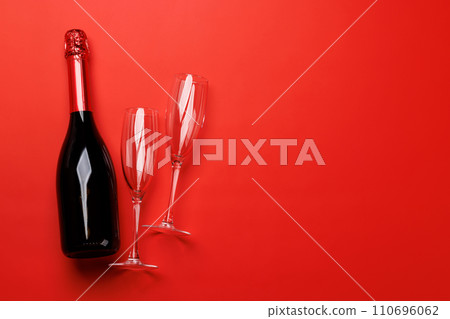 Champagne glasses and bottle on a red background with text space 110696062