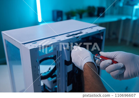 Rear view of a young man installing graphics card to his desktop computer at home. Rear view of a young man installing graphics card to his desktop computer at home. 110696607