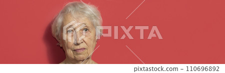 Close up portrait of senior woman against red background Close up portrait of senior woman against red background 110696892