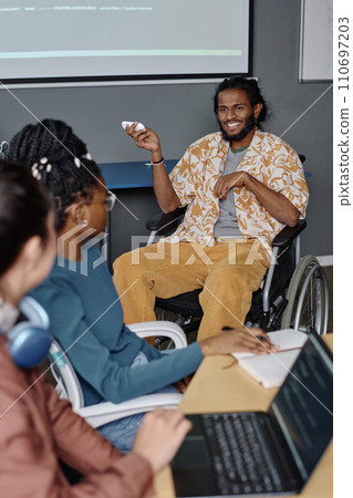 Man with disability in stylish outfit giving presentation to his colleagues at business conference 110697203