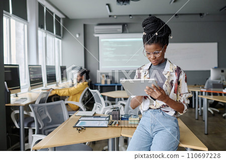 Young black engineer with braids typing on tablet, her male colleague working on background 110697228