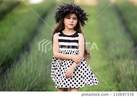 A small and beautiful girl walks in a park with a lavender field A small and beautiful girl walks in a park with a lavender field 110697338