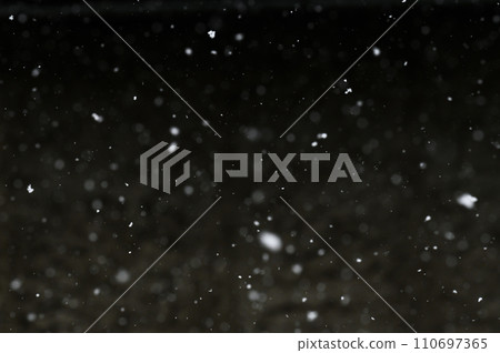 Bokeh of white snow on a black background. Snowfall - design element. 110697365