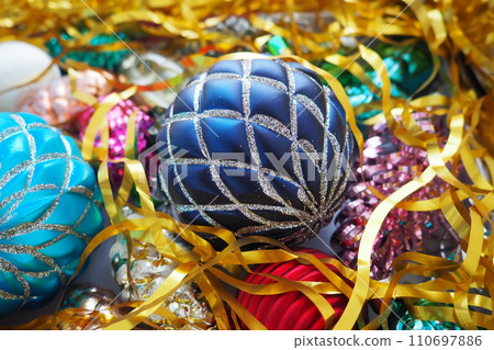 Christmas balls, foil cones and decorations with gold tinsel close-up. Beautiful bright decorative balls of a modern fashionable design with intertwining stripes. New Year's and Christmas Xmas 110697886