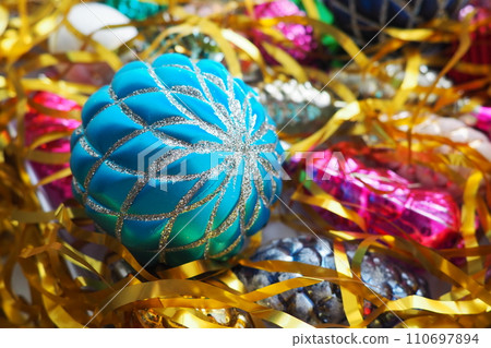 Christmas balls, foil cones and decorations with gold tinsel close-up. Beautiful bright decorative balls of a modern fashionable design with intertwining stripes. New Year's and Christmas Xmas Christmas balls, foil cones and decorations with gold tinsel close-up. Beautiful bright decorative balls of a modern fashionable design with intertwining stripes. New Year's and Christmas Xmas 110697894