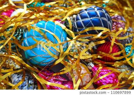 Christmas balls, foil cones and decorations with gold tinsel close-up. Beautiful bright decorative balls of a modern fashionable design with intertwining stripes. New Year's and Christmas Xmas 110697899
