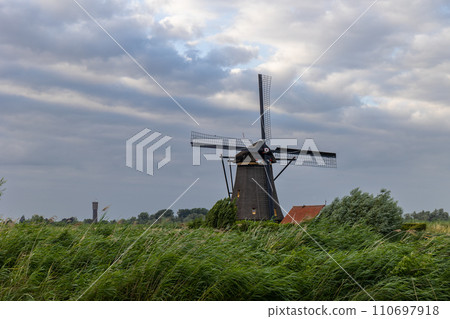 Beautiful wooden windmills at sunset in the Dutch village of Kinderdijk. Windmills run on the wind. The beautiful Dutch canals are filled with water. Beautiful sunset. 110697918