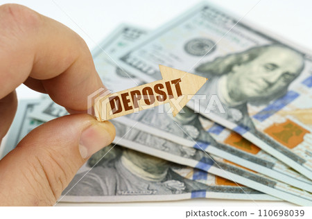 In the hands of a man is an arrow with the inscription - DEPOSIT, in the background there are dollars. 110698039