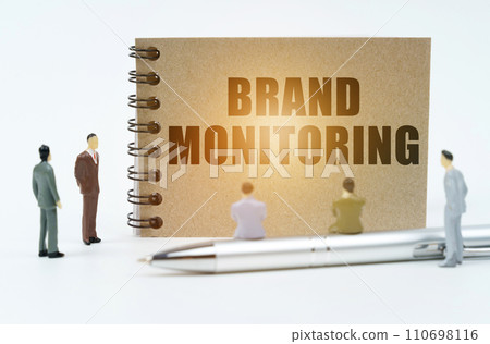 On a white background, figures of businessmen, a pen and a notepad with the inscription - Brand Monitoring 110698116