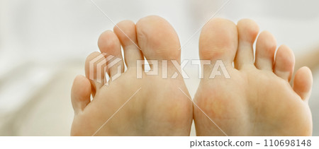 Two feet of a woman pressed against each other. Toes close-up, foot partially visible. 110698148