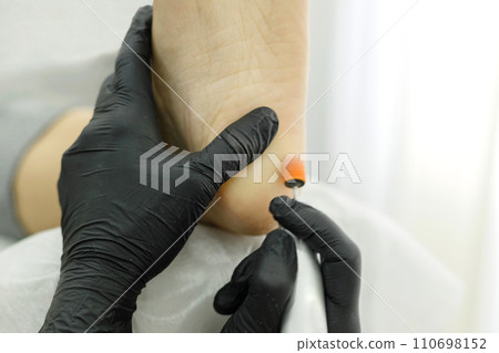 Master hardware pedicure during operation. Nail processing and milling Master hardware pedicure during operation. Nail processing and milling 110698152