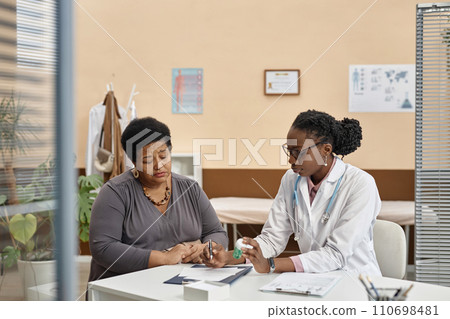 Medium shot of Black woman physician prescribing pills to mature African American female patient during visit in clinic office Medium shot of Black woman physician prescribing pills to mature African American female patient during visit in clinic office 110698481
