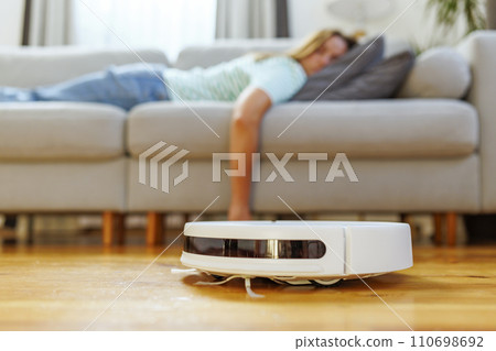 Woman Relaxing with Robotic Vacuum Cleaner at Work Woman Relaxing with Robotic Vacuum Cleaner at Work 110698692