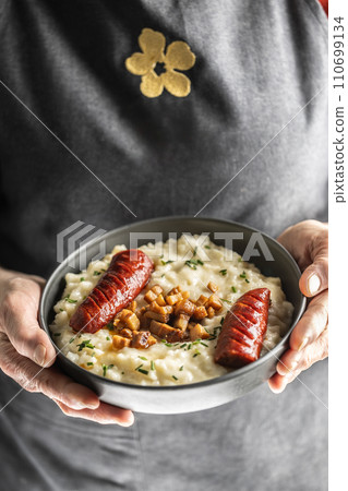 The hands of a senior home cook hold a plate with a national Slovak dish - Bryndzove Halusky. The hands of a senior home cook hold a plate with a national Slovak dish - Bryndzove Halusky. 110699134