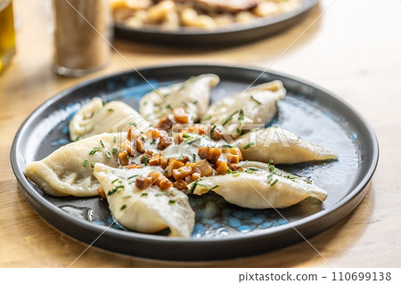 Filled pirohy dish served with fried bacon, fresh chive, and sour cream 110699138