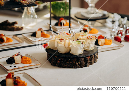 Assortment of delicious snacks on the open buffet festive table in restaurant. Catering plate Assortment of delicious snacks on the open buffet festive table in restaurant. Catering plate 110700221