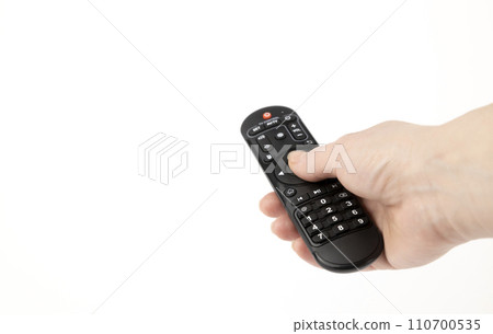 The TV remote control. The remote control in a woman's hand. The concept of technology. Manually pressing the buttons on the remote control. The TV remote control. The remote control in a woman's hand. The concept of technology. Manually pressing the buttons on the remote control. 110700535