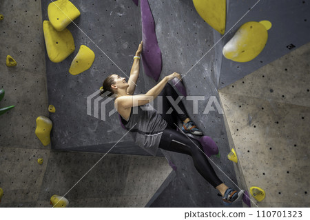 Happy woman climbing colored artificial wall in Happy woman climbing colored artificial wall in 110701323
