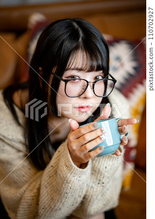 坐在客廳沙發上喝咖啡的女人 坐在客廳沙發上喝咖啡的女人 110702927