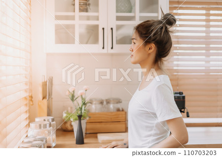 Woman looking out the window from white warm kitchen. Woman looking out the window from white warm kitchen. 110703203