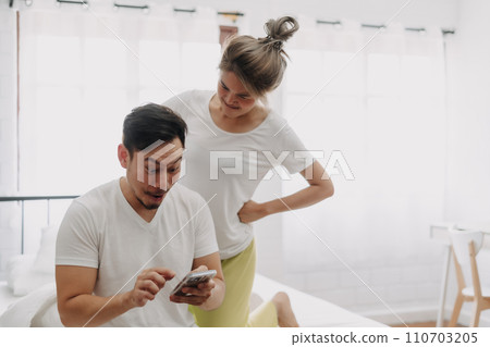 Funny couple. Wife peeking husband who chatting on the smartphone. 110703205