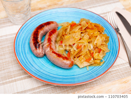 Roasted tasty sausages served with side dish of cabbage stewed 110703405