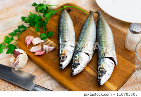 Whole mackerel carcasses, parsley, garlic are on wooden background Whole mackerel carcasses, parsley, garlic are on wooden background 110703503