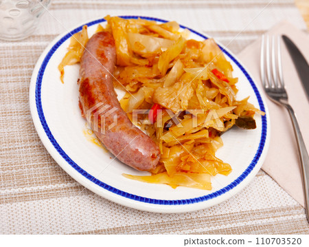 Roasted tasty sausages served with side dish of cabbage stewed 110703520