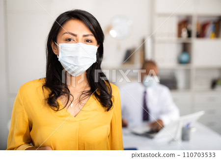 Confident businesswoman in medical mask inviting to office 110703533