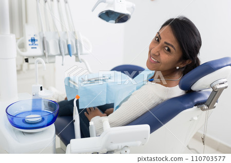 Cheerful female patient waiting for examination in dental chair Cheerful female patient waiting for examination in dental chair 110703577